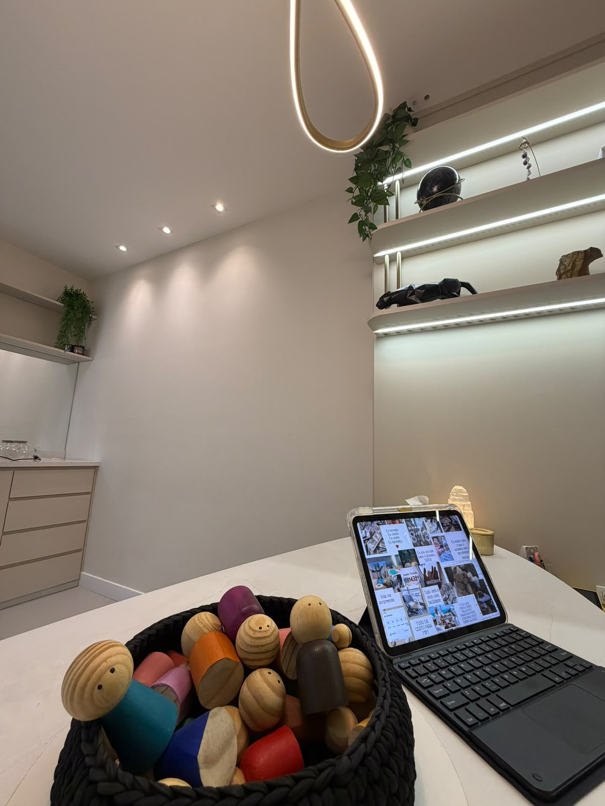 Cesta com bonecos de madeira usados na constelação familiar e tablet sobre a mesa do consultório